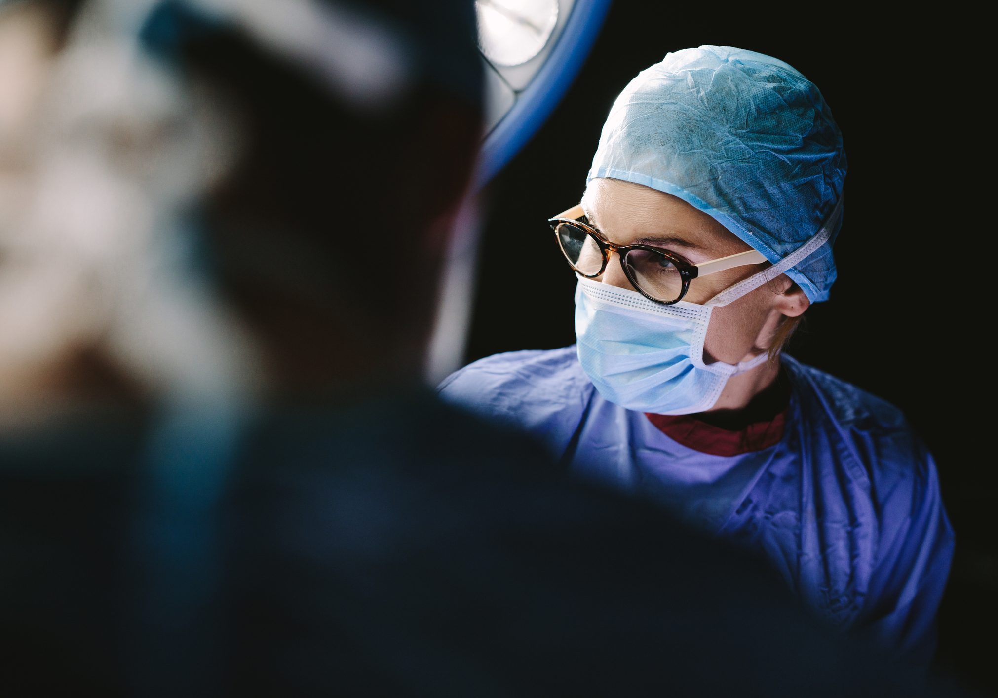 Surgeon wearing medical mask with medical team performing surgery in hospital operation theater.